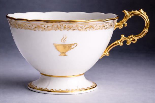 Elegant porcelain teacup with gold detailing and ornate handle, part of Yūgen Tea Atelier branding