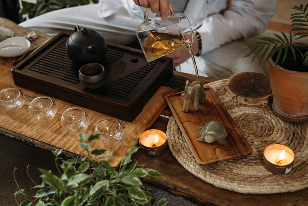 Tea ritual preparation for Yūgen Tea Atelier featuring tea being poured over a ceremonial set with teaware and candles.
