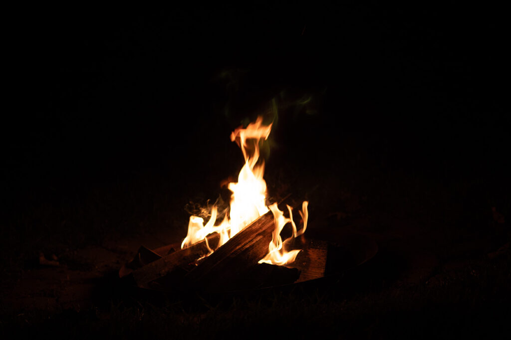 Small fire burning in a fire pit at night with glowing flames and dark surroundings