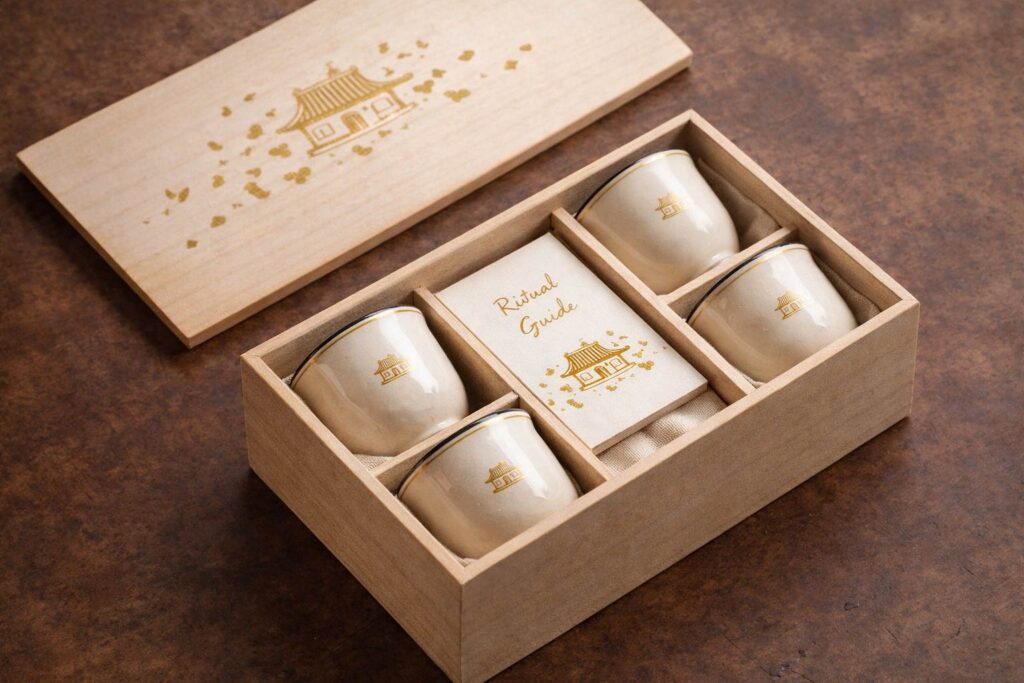 Yūgen Tea Atelier collection packaging featuring a luxury tea ritual set with porcelain cups in a wooden box.